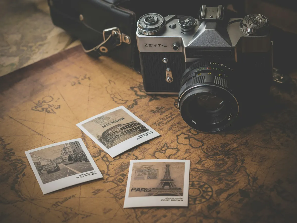 Appareil photo argentique posé sur une carte du monde avec des tirages